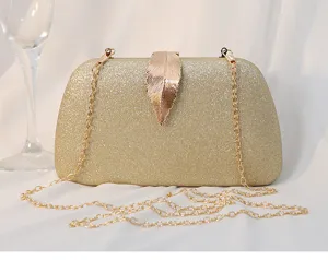 Close-up detail of golden glitter evening clutch with metal leaf clasp and chain