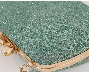 Nahaufnahme einer grünen Glitzer-Abendtasche mit goldfarbenem herzförmigem Verschluss.