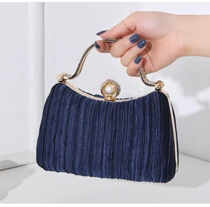 Nahaufnahme einer eleganten marineblauen Plissee-Abendtasche mit Perlenverschluss