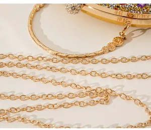 Détail rapproché de la chaîne dorée et des strass sur une pochette de soirée de luxe