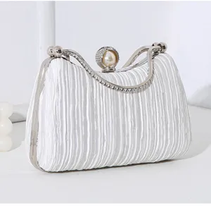 Nahaufnahme der weißen plissierten Clutch mit Details zum Perlen- und Strassgriff.
