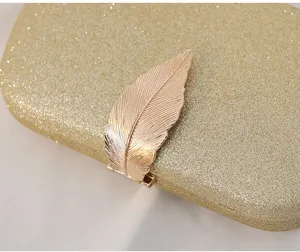 Detailed macro shot showcasing the elegant golden leaf clasp on a glitter evening clutch bag
