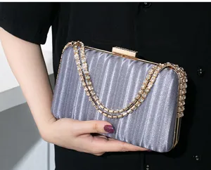 Detailansicht einer silbernen Abendtasche mit Strassketten, in der Hand gehalten.
