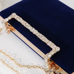 Elegante dunkelblaue Samt-Abendtasche mit funkelndem Strassgriff und langer goldener Kette.