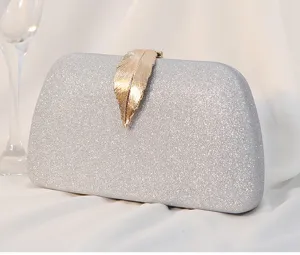 Close-up of a silver glitter evening clutch bag featuring an elegant gold leaf-shaped clasp