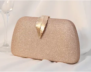 Close-up view of a golden glitter evening clutch bag featuring a metallic leaf ornament