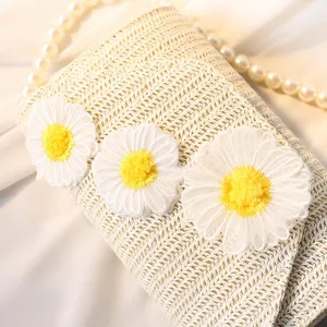 Gewebte Stroh-Umhängetasche mit Gänseblümchen-Applikationen und eleganter Perlenkette