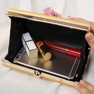 Goldene Abend-Clutch mit Blumen offen gezeigt mit Smartphone und Kosmetik im Inneren
