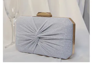Nahaufnahme einer silbernen Falten-Abendtasche mit Glitzertextur und goldenem Verschluss.