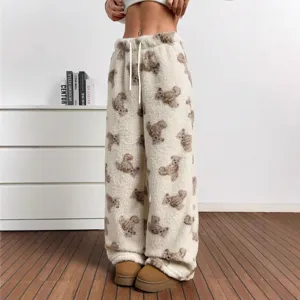 Close-up of cozy white fuzzy trousers featuring a cute all-over brown teddy bear print