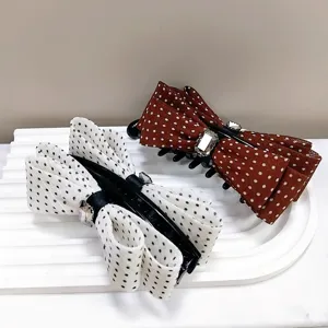 Detail view of polka dot bow banana hair clips with jewel accents on white tray