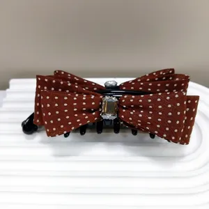 Detailed macro view of a brown polka dot bow banana hair clip with sparkling crystal accents.