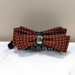 Detailed view of a brown polka dot banana hair clip with elegant crystal embellishment