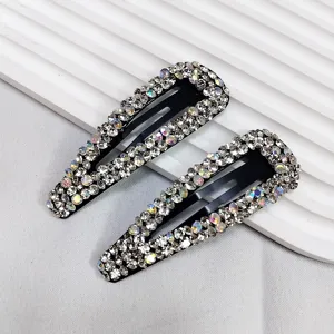 Détail de barrettes à strass étincelantes avec des cristaux colorés sur fond blanc.