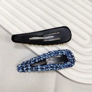 Détail macro de pinces clic-clac gouttes en strass bleu avec support en métal noir