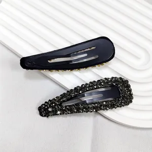 Vue rapprochée de barrettes BB en métal noir ornées de strass gris fumé et dorés