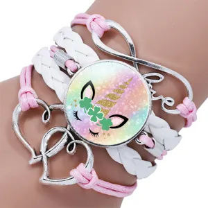 Close-up of unicorn time gem bracelet with braided pink and white straps and Love charm.