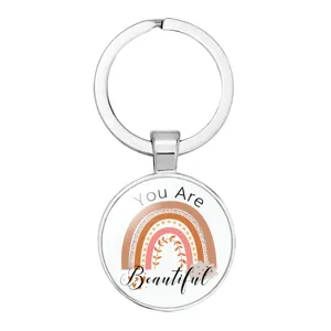 Close-up of a silver keychain pendant with a boho rainbow and motivational text.