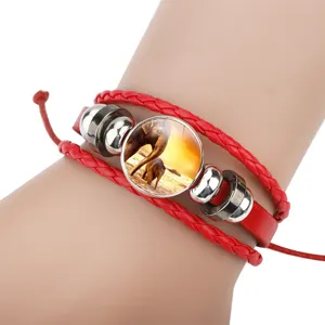 Close-up detail of a red braided leather elephant bracelet featuring a sunset charm