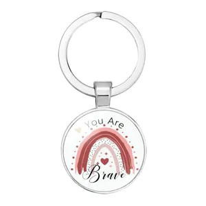 Detailed view of a circular metal keychain with a rainbow and 'You Are Brave' text.