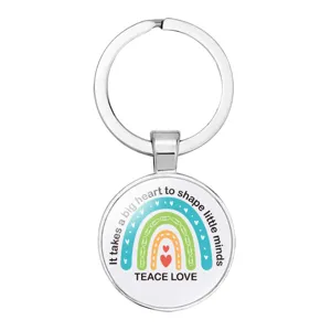 Detail view of a round silver metal teacher keychain with rainbow and heart design