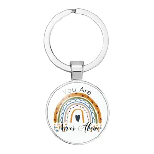 Close-up view of a rainbow metal keychain with 'You Are Never Alone' inspirational text