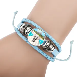 Close-up of blue braided leather bracelet with a circular elephant landscape charm.