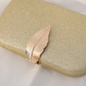Elegant gold glitter evening clutch bag featuring a detailed golden metal leaf shaped clasp