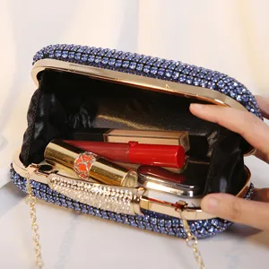 Elegante blaue Abendtasche mit Strassbesatz, geöffnet mit diversen Make-up-Accessoires