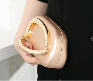 Detailansicht des herzförmigen Goldgriffs an einer champagnerfarbenen Abendtasche