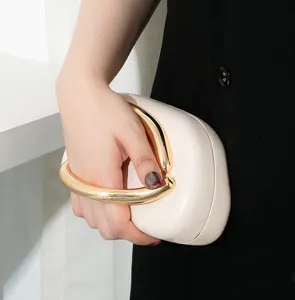 Nahaufnahme einer eleganten cremefarbenen Clutch mit goldenem Metallgriff für Gala-Abende