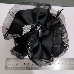 Detailed view of black satin scrunchie with rhinestones and mesh edge shown with ruler scale