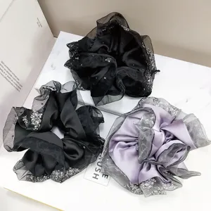 Detail view of large satin scrunchies with elegant gauze edges and sparkly rhinestones.