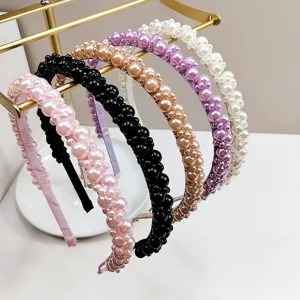 Elegant handmade pearl headbands in multiple colors displayed on a gold jewelry stand.