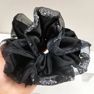 Close-up of black satin scrunchie with glittery mesh edges and rhinestone detail