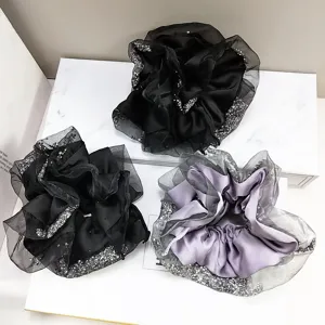 Detailed view of large satin scrunchies featuring elegant mesh edges and sparkling rhinestones.