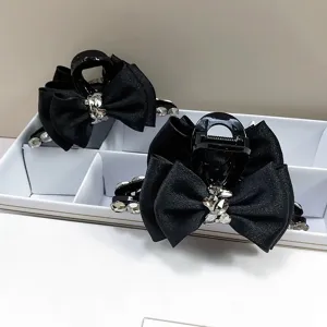 Detailopname van elegante zwarte haarklemmen met een strik en sprankelende K9-kristallen