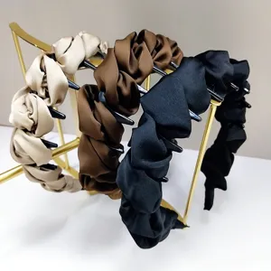 Détail de trois élégants serre-têtes en satin froncé de couleur beige, marron et noir.