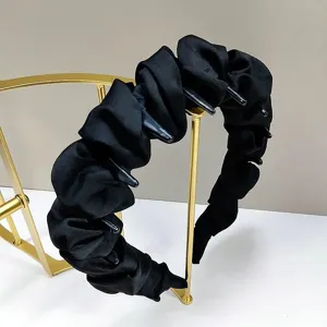 Détail du serre-tête en satin noir avec dents antidérapantes et texture plissée.