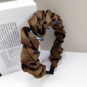 Gros plan sur le serre-tête en satin marron avec froufrous et dents antidérapantes