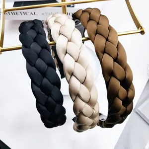 Lot de trois serre-têtes tressés en noir, beige et marron sur un présentoir doré