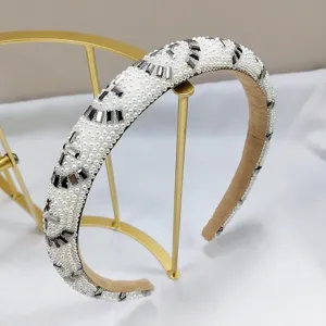 Primer plano de elegante diadema de perlas blancas con cristales oscuros en soporte oro