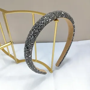 Primer plano de una diadema estrecha gris plomo brillante en soporte dorado
