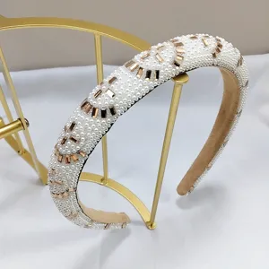 Detalle de una elegante diadema con perlas blancas y cristales dorados sobre un soporte