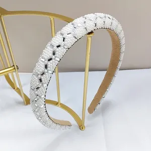 Nahaufnahme von weißen Perlen und glitzernden Strasssteinen auf einem Stirnband für Damen.