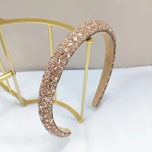 Primer plano elegante de una diadema con pedrería de oro champán en soporte dorado
