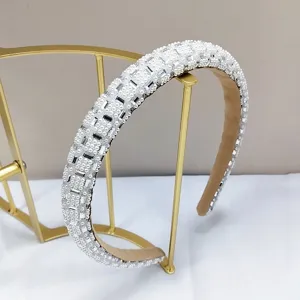 Gedetailleerde weergave van een elegante brede haarband met witte parels en kristallen.