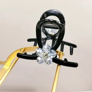 Gros plan d'une pince à cheveux de luxe avec fleur en cristal sur fond noir brillant