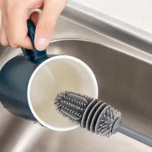 Detail showing the oval silicone brush head cleaning the inside of a blue ceramic mug
