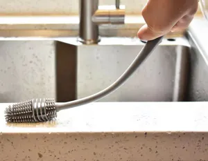 Close-up of flexible gray long-handle silicone cup brush showing its bending capability